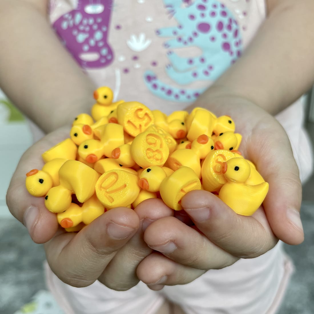 Child holding a handful of small yellow numbered ducks in their hands