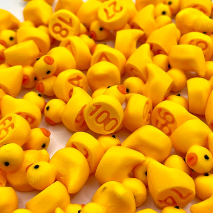 Close-up of many small yellow numbered ducks showing numbers like 100, 27 and 4